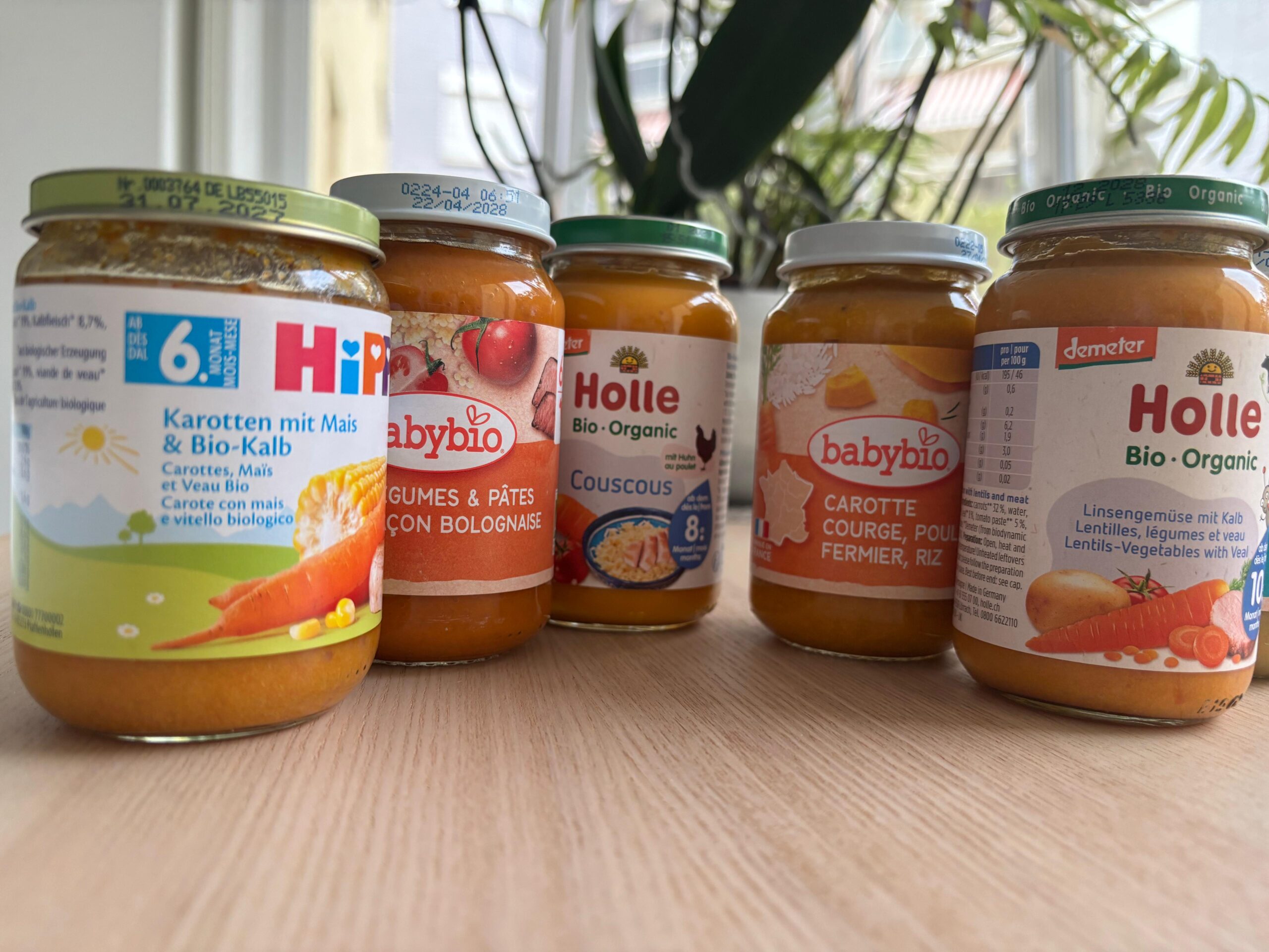 Des petits pots HiPP, Babybio et Holle alignés sur une table.