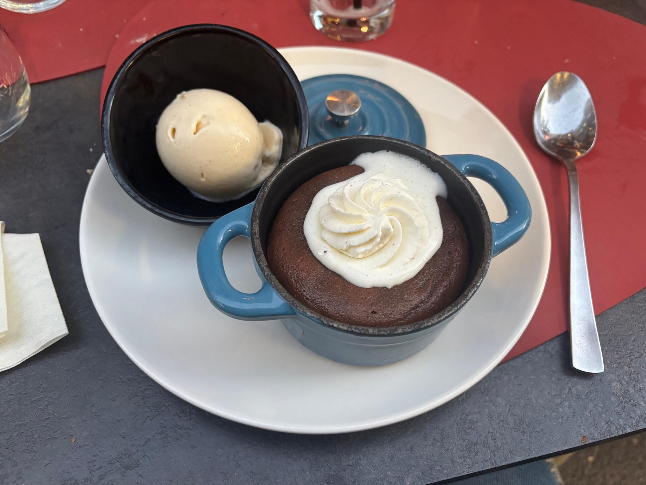 Le mi-cuit au chocolat servi dans une cocotte bleue avec une boule de glace.